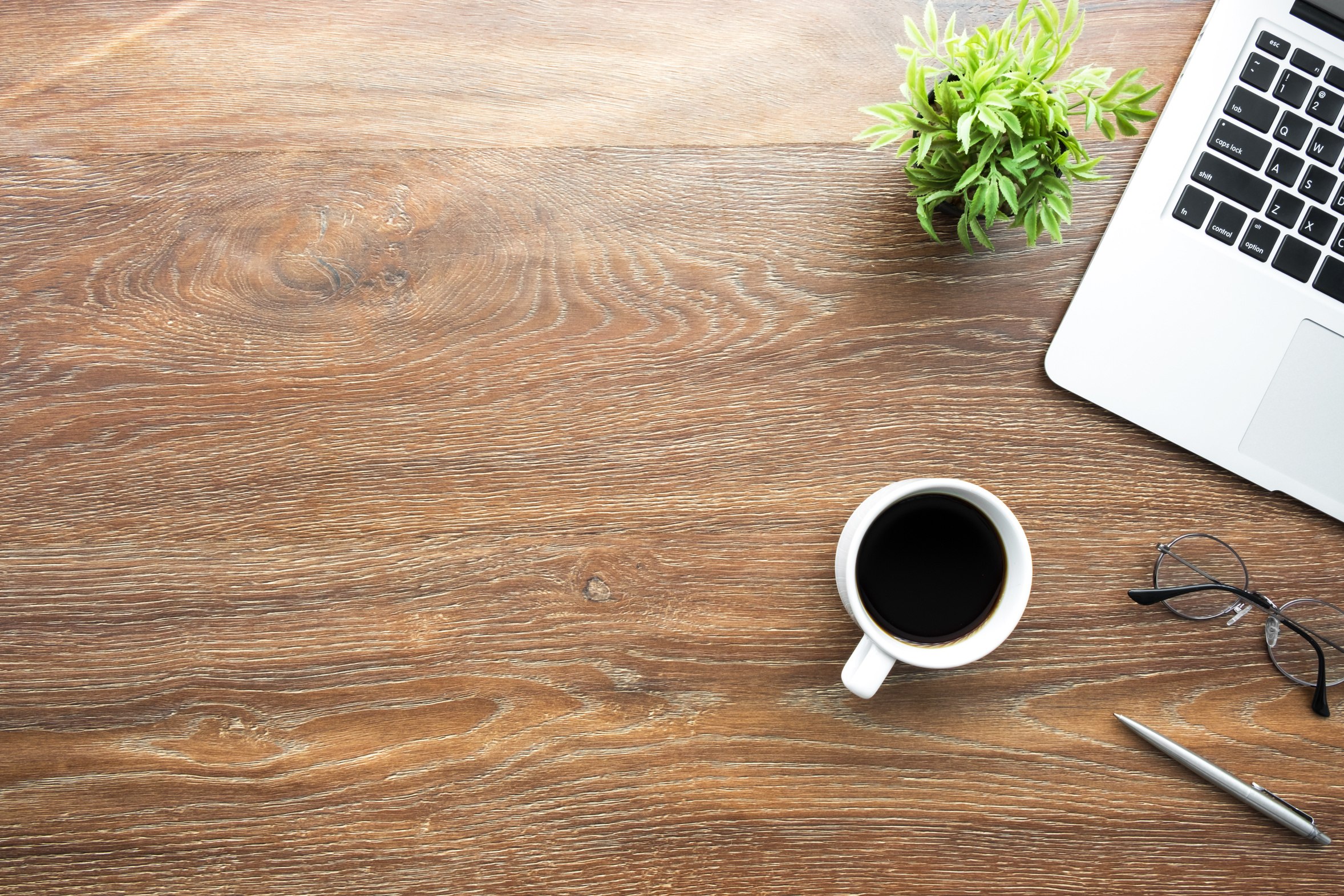 A desk with a laptop, coffee, and planning supplies in morning light