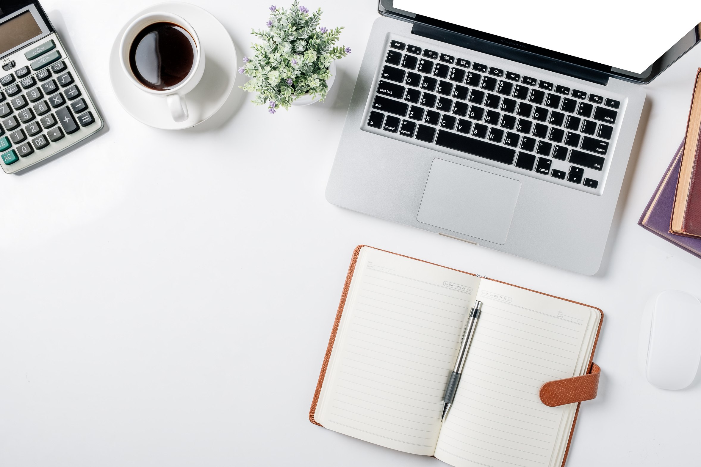 A desk with a notebook, calculator, and coffee cup laid out for budget planning