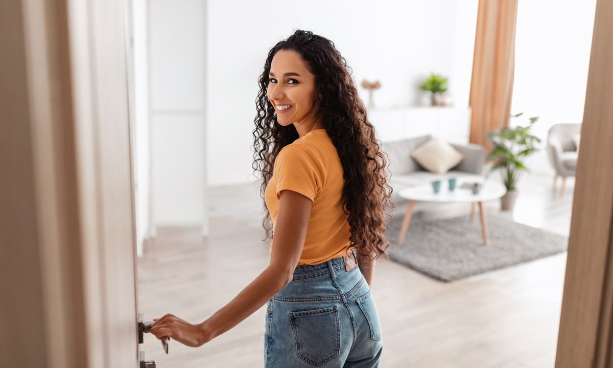 A young woman opening the door of her new furnished home