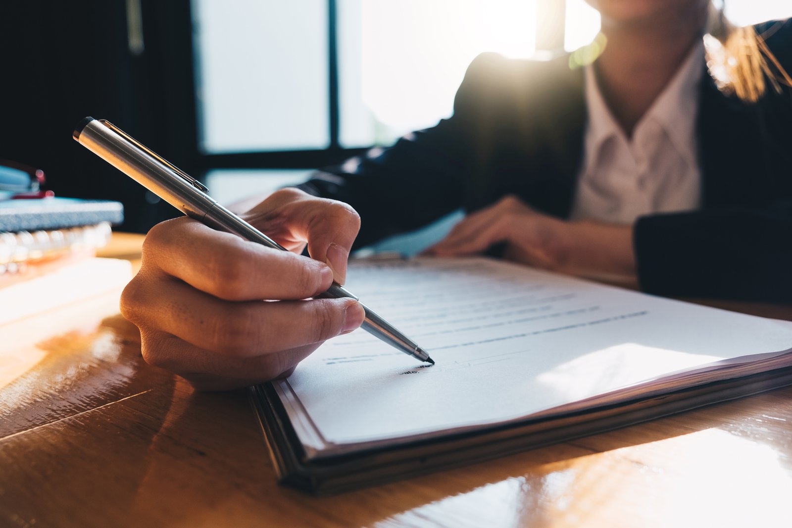 A close-up of two people shaking hands over a signed lease agreement on a desk