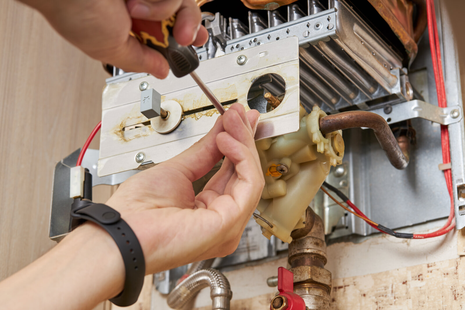 A service technician repairing a water heater inside a home