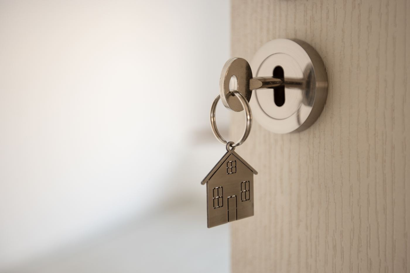 A hand holding a house key at an open front door