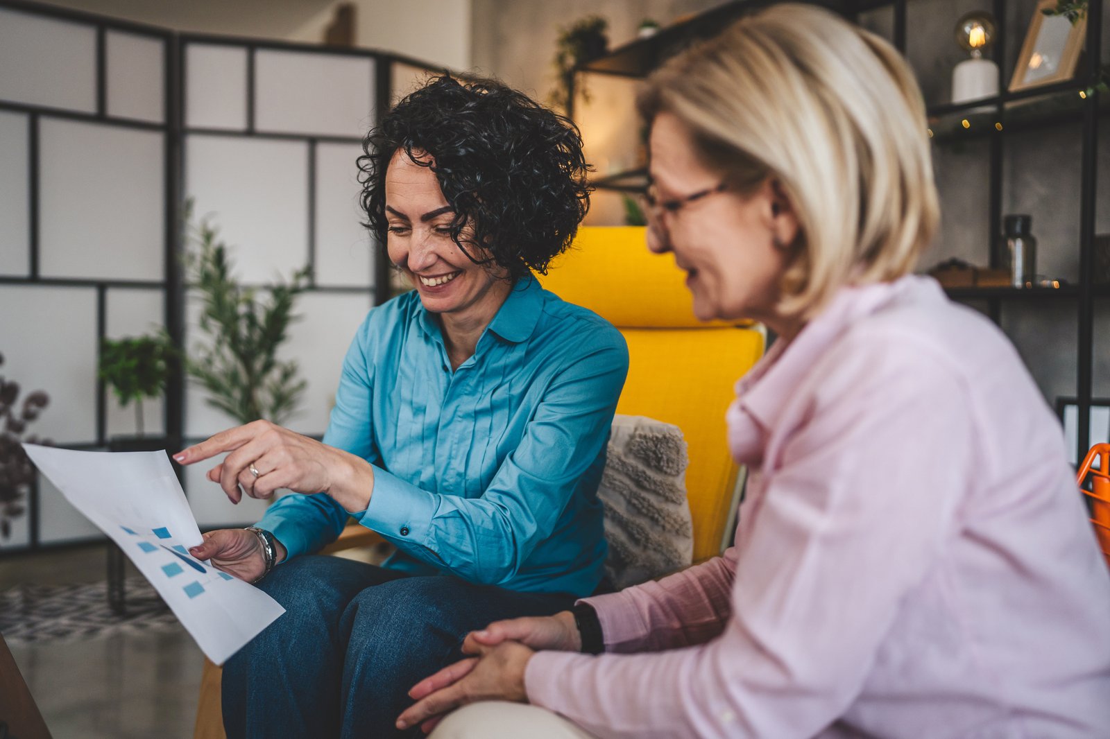 Two colleagues sitting together at home reviewing a paper document in consultation