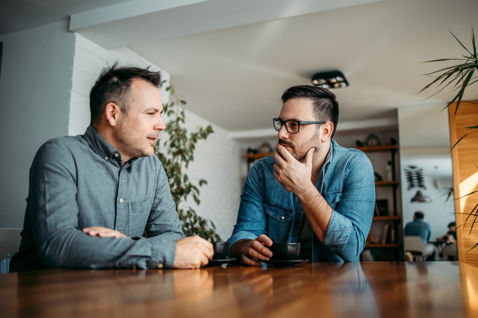 Two colleagues having a relaxed conversation at a desk with documents