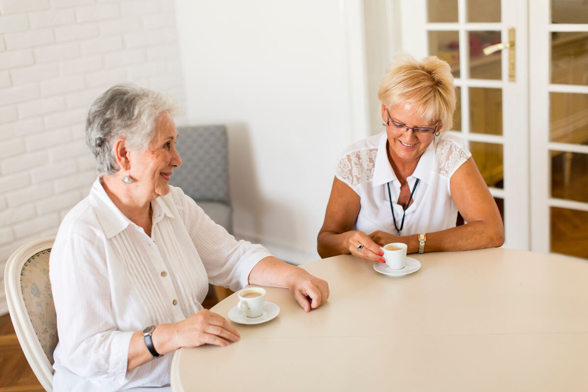 Two older women drinking coffee together at home